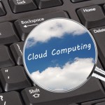 Magnifying glass showing clouds on a keyboard. Concept for cloud